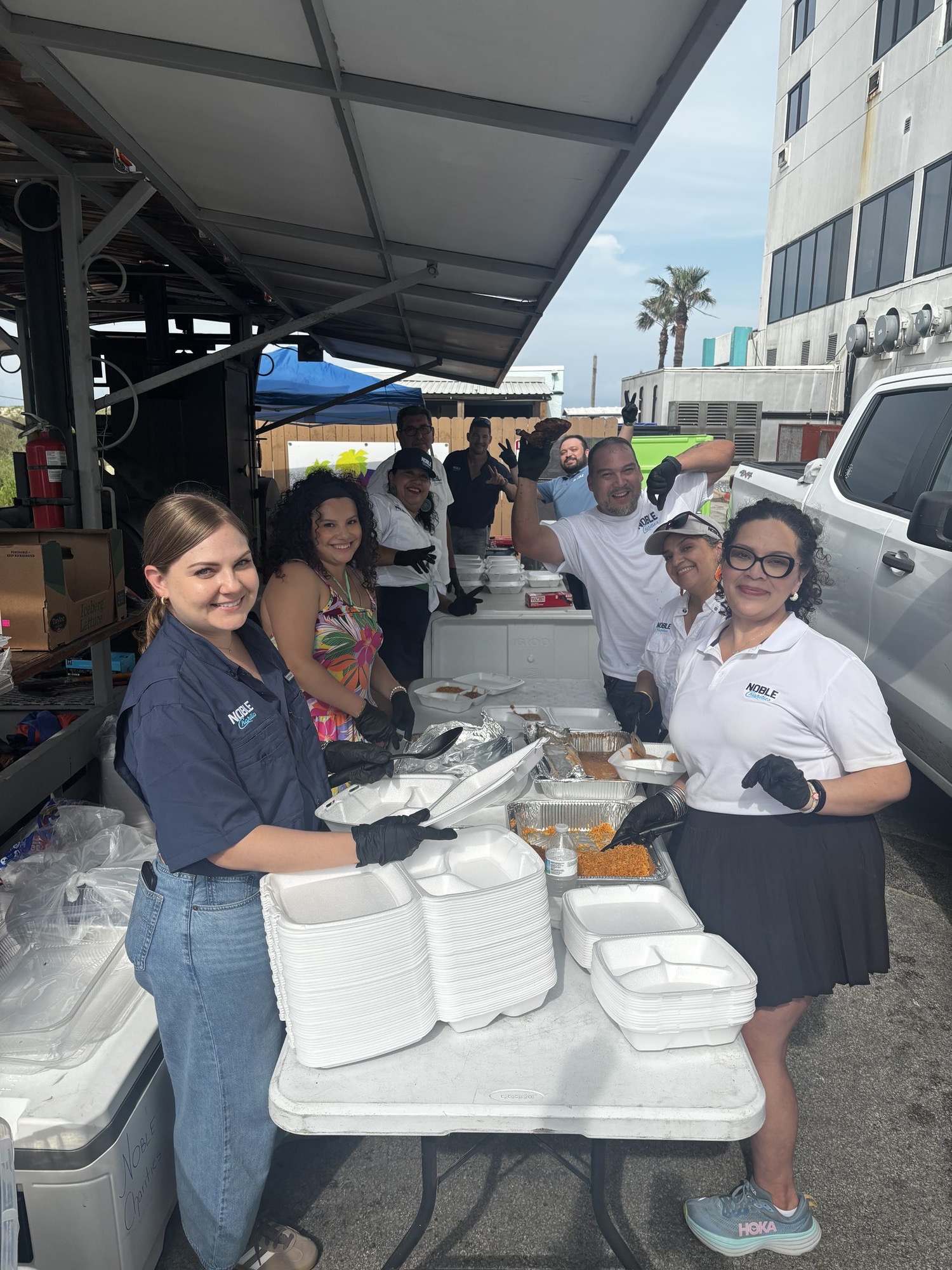Noble Charities volunteers plating and handing out meals under a canopy at the SPI Police Games