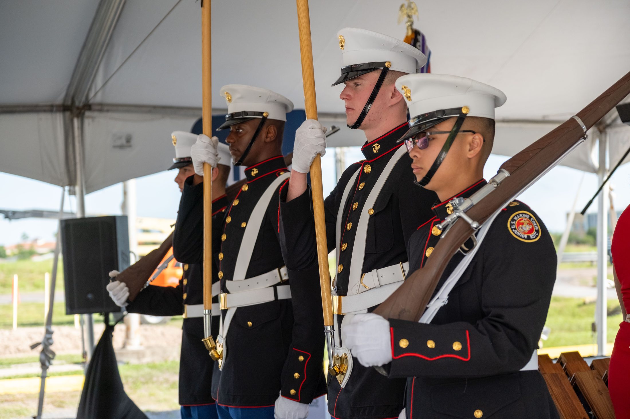 A United States Marine Corps color guard standing at attention with rifles and flags