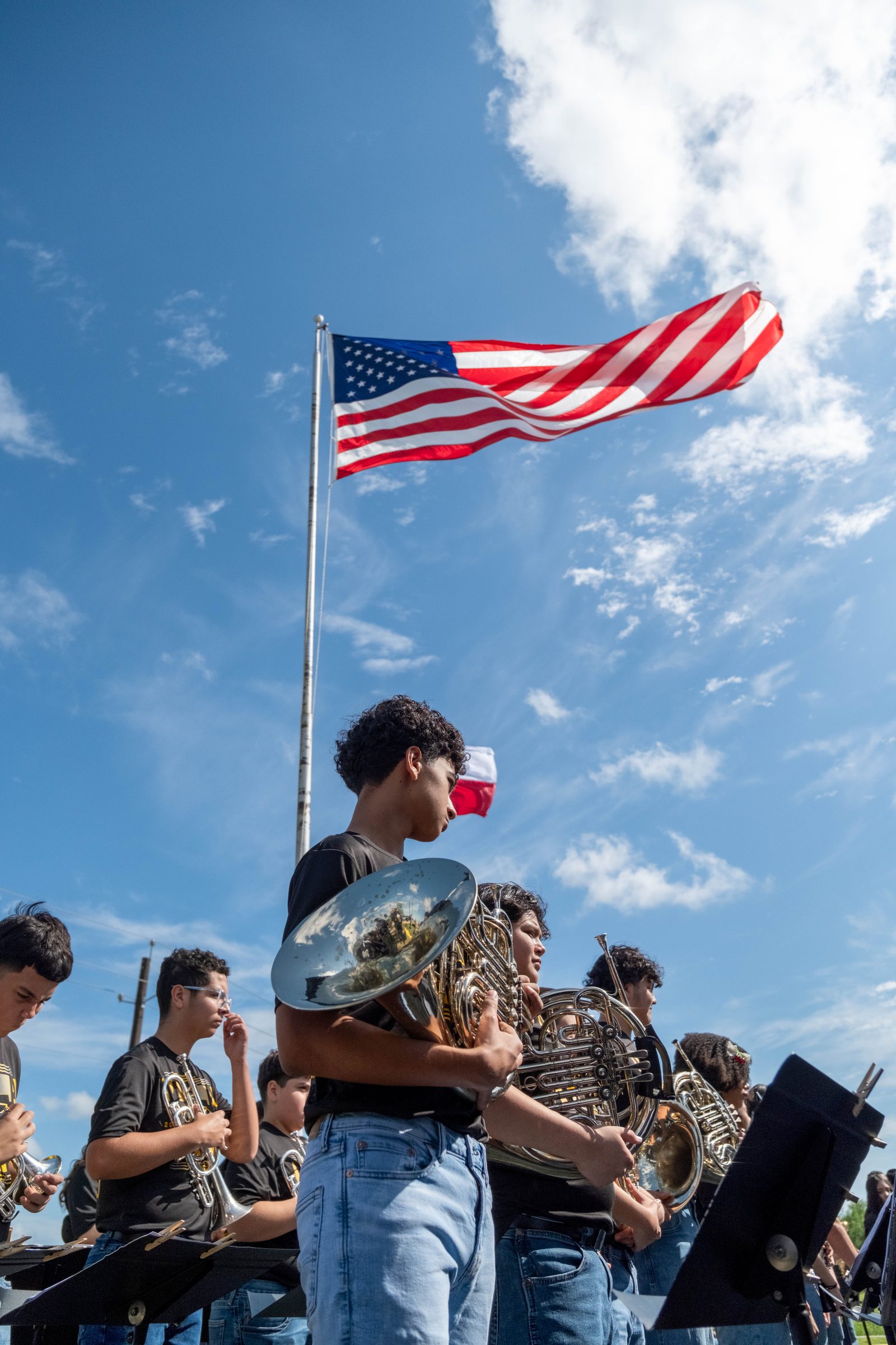 A high-school band performing beneath the American and Texas flags
