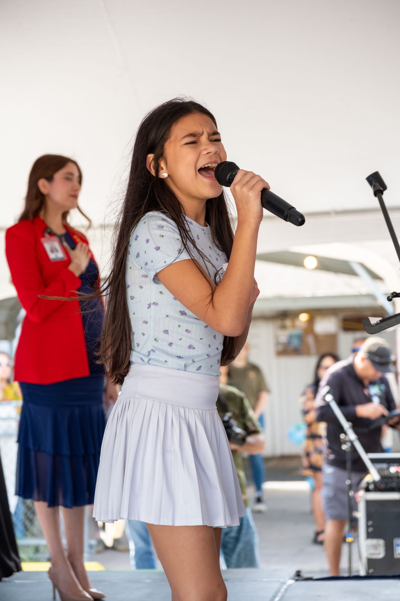 A young singer performing the national anthem into a microphone