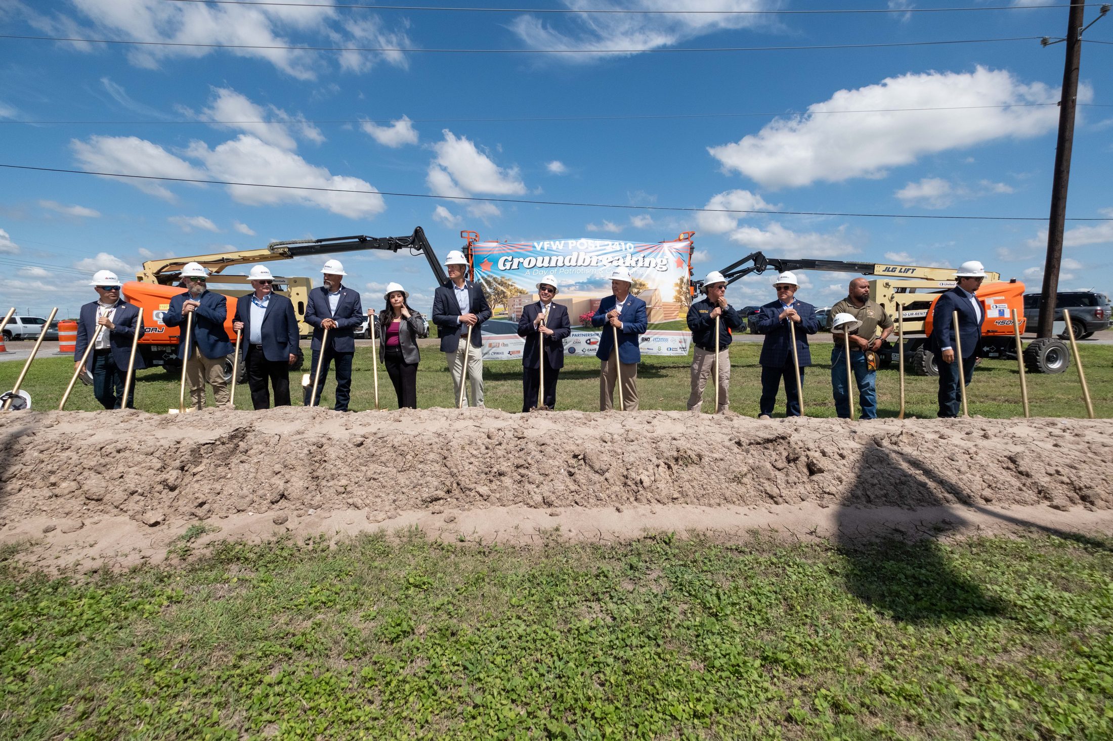 A long line of veterans, officials, and project partners turning the first dirt with ceremonial shovels