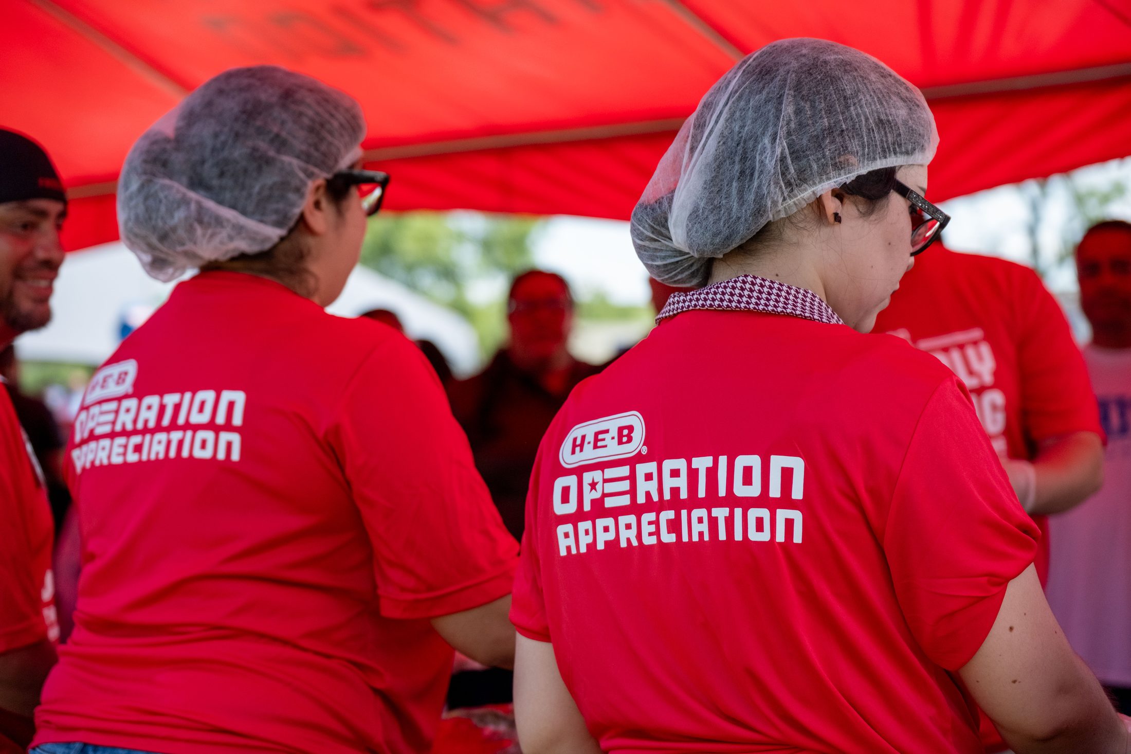 H-E-B Operation Appreciation volunteers in red shirts serving food after the ceremony