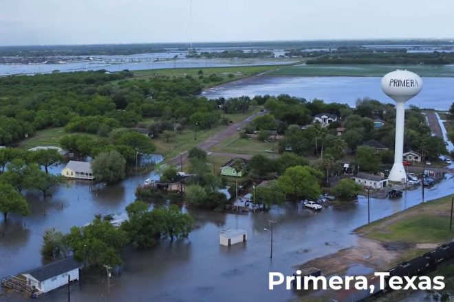 Aerial view of floodwater standing across streets and yards in Primera, Texas, with the town water tower at right